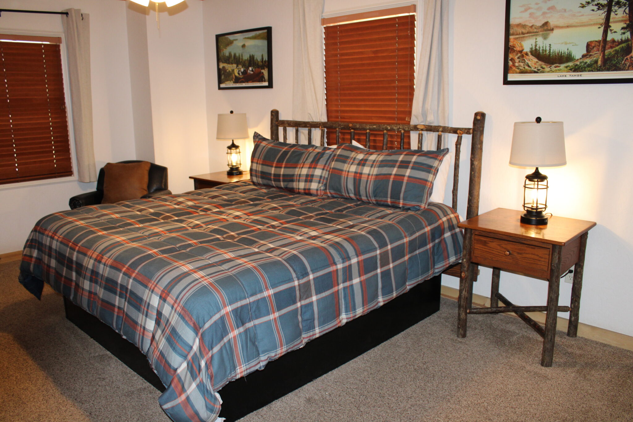 A wide view of a guest room with a plaid bedspread, wooden furniture, and lamps on nightstands.