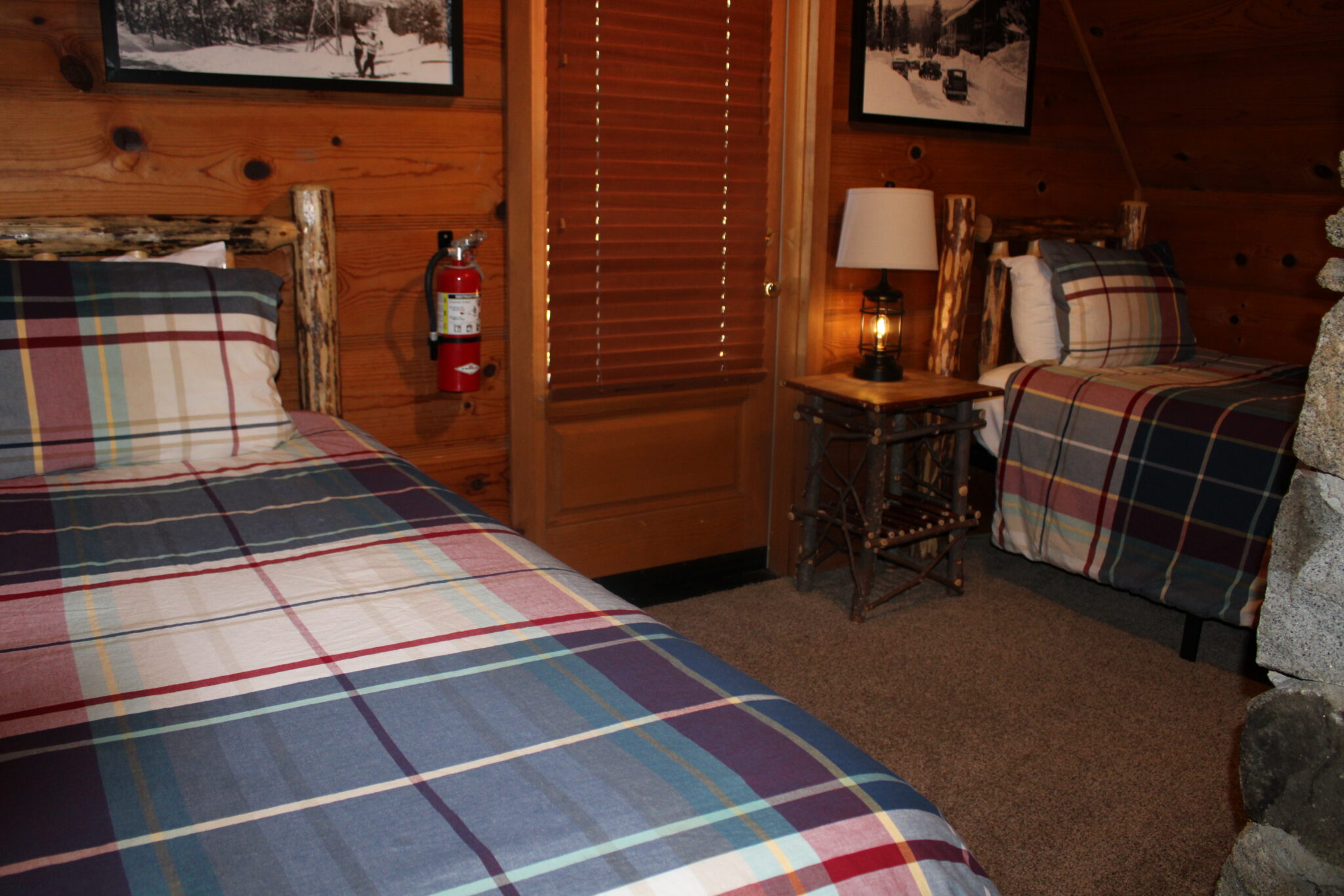 A cozy room with two beds, wooden headboards, and plaid bedspreads.